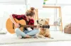 愛犬の隣でギターを引く女性