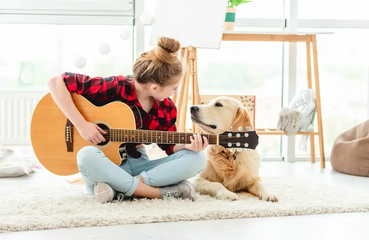 愛犬の隣でギターを引く女性